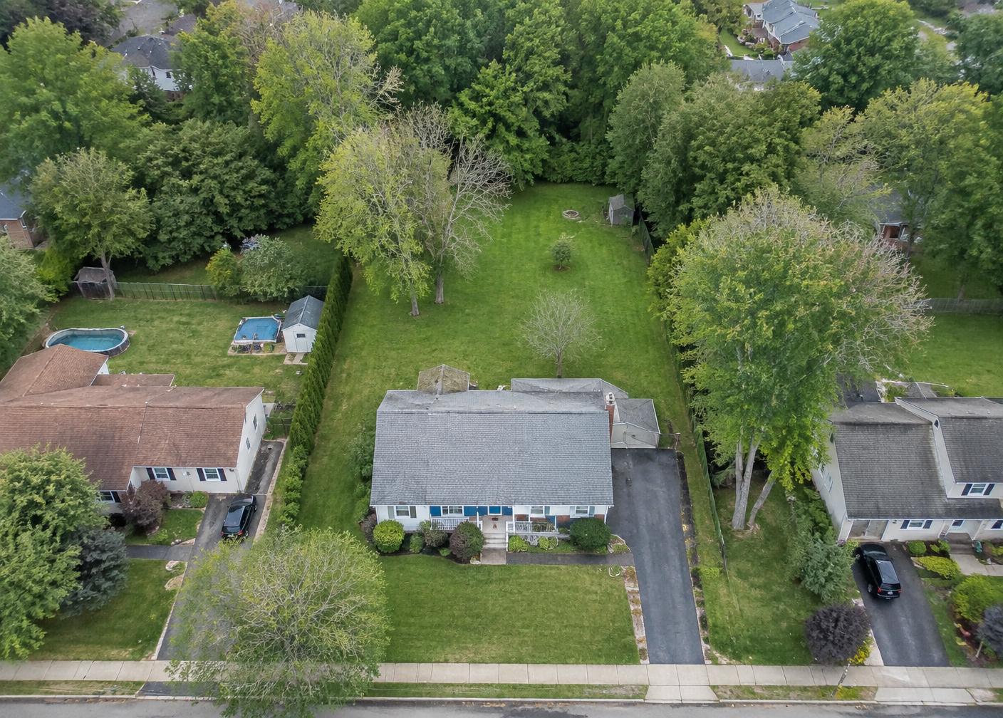 Aerial view of a house set forward on a deep green lot